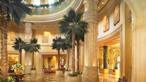 A grand lobby with high ceilings, ornate columns, and a patterned floor. There are several zebra-striped chairs and potted plants. - The Palace of the Lost City at Sun City Resort (Moses Kotane)