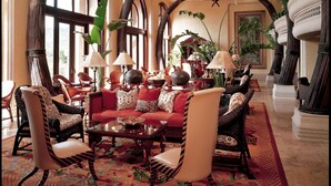 A spacious lobby with high arched ceilings, large windows, and a central seating area with a red sofa and multiple chairs. - The Palace of the Lost City at Sun City Resort (Moses Kotane)