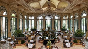 A grand dining hall with high arched windows, ornate columns, and a central fountain. - The Palace of the Lost City at Sun City Resort (Moses Kotane)