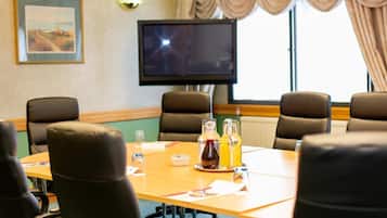 A conference room with a large table, chairs, a television, and various beverages.