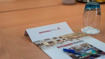 Een brochure van Britannia Hotels met een helder glas en een wit kaartje op een houten tafel.
