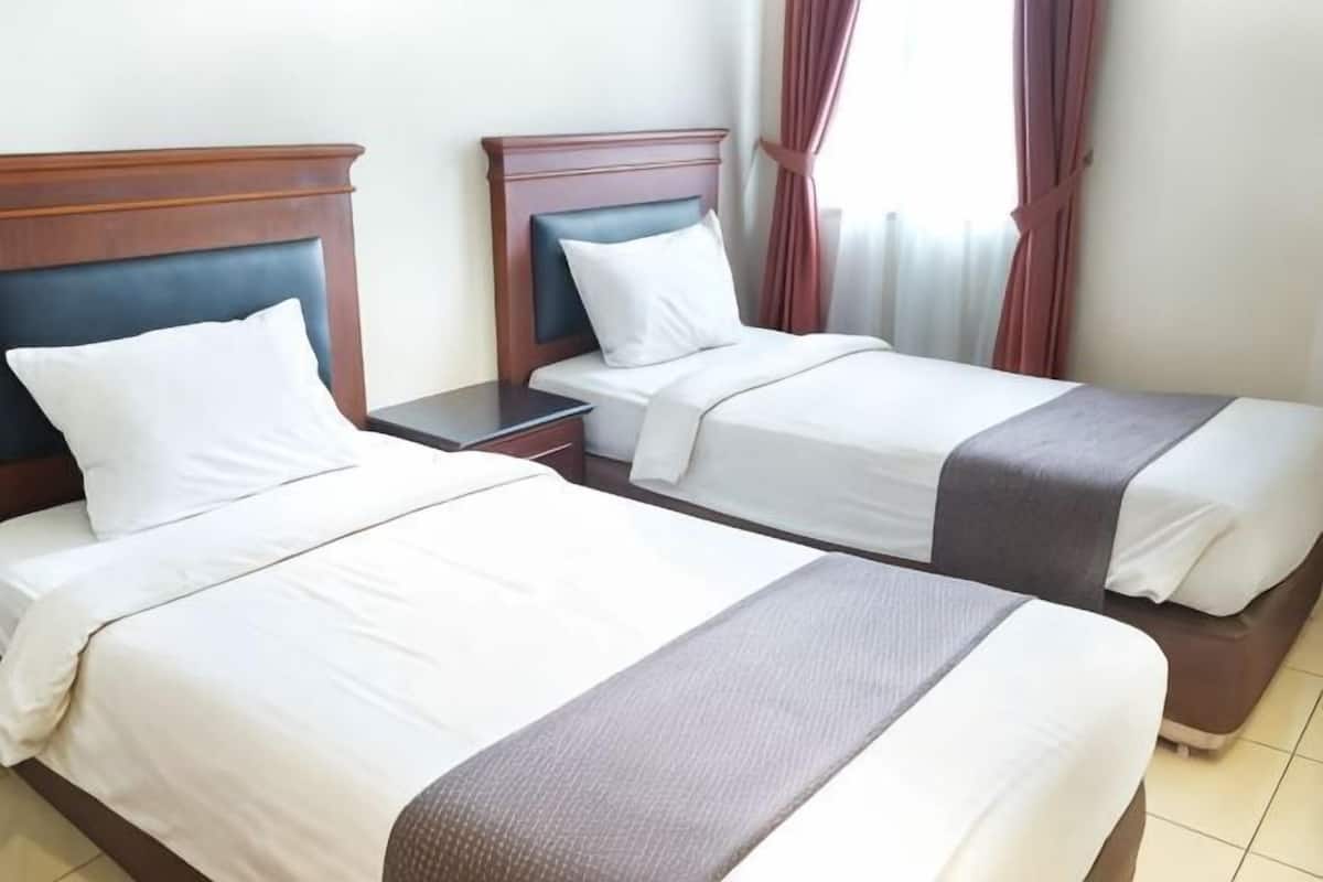 Two single beds with wooden headboards, white bedding, and a nightstand between them.