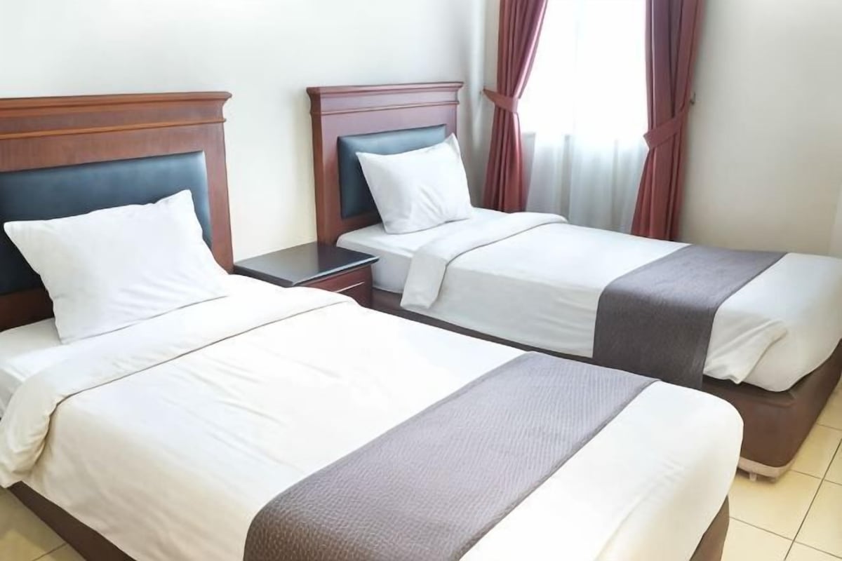 Two single beds with wooden headboards, white linens, and a brown accent.