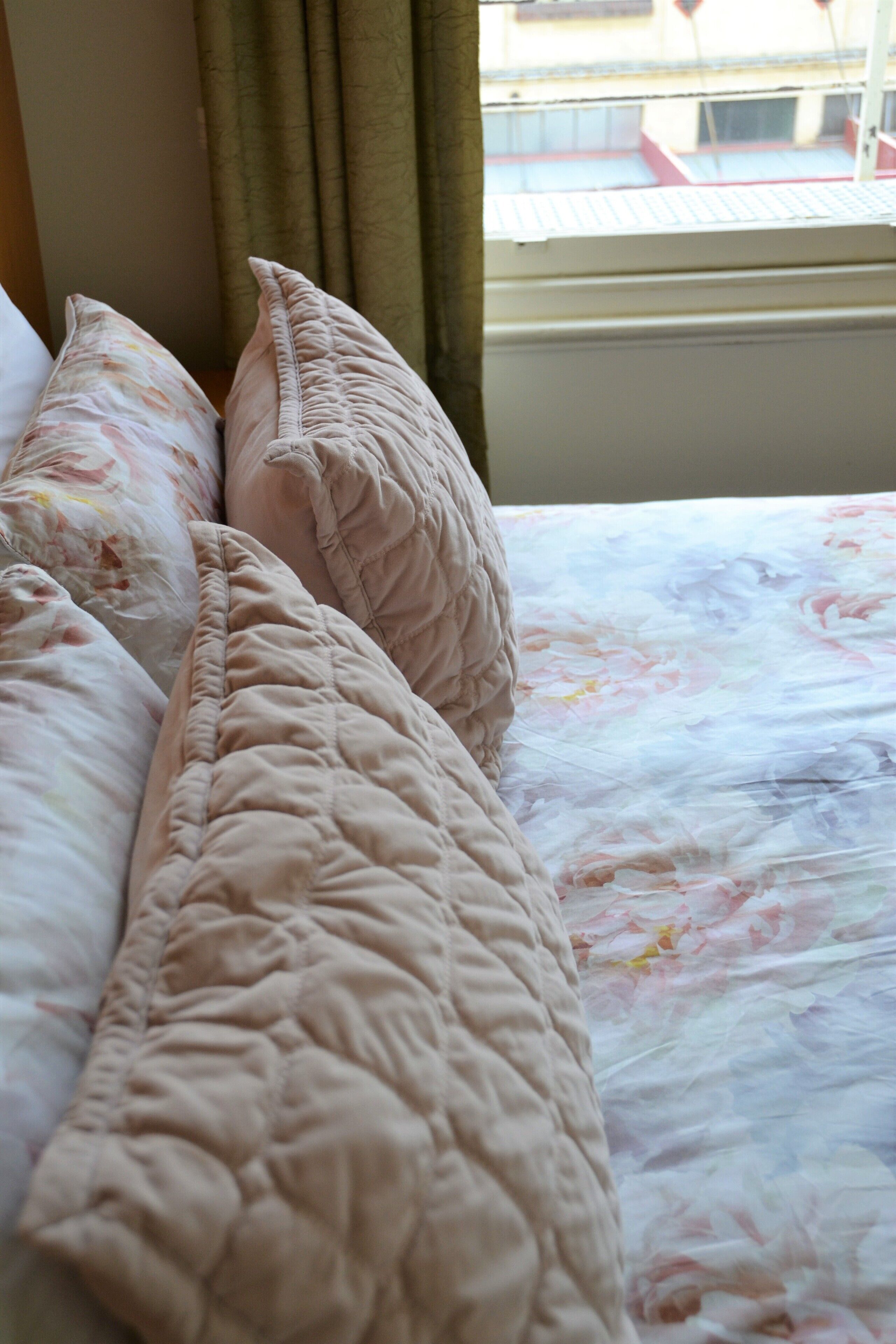 A bed with a floral bedspread and two pillows.