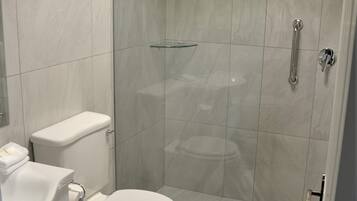 Ein modernes Badezimmer mit Toilette, Waschbecken und einer Dusche mit Glastrennwand.
