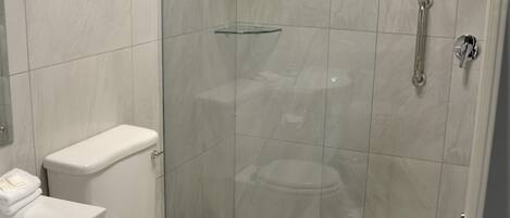 A modern bathroom with a toilet, sink, and glass-enclosed shower area.