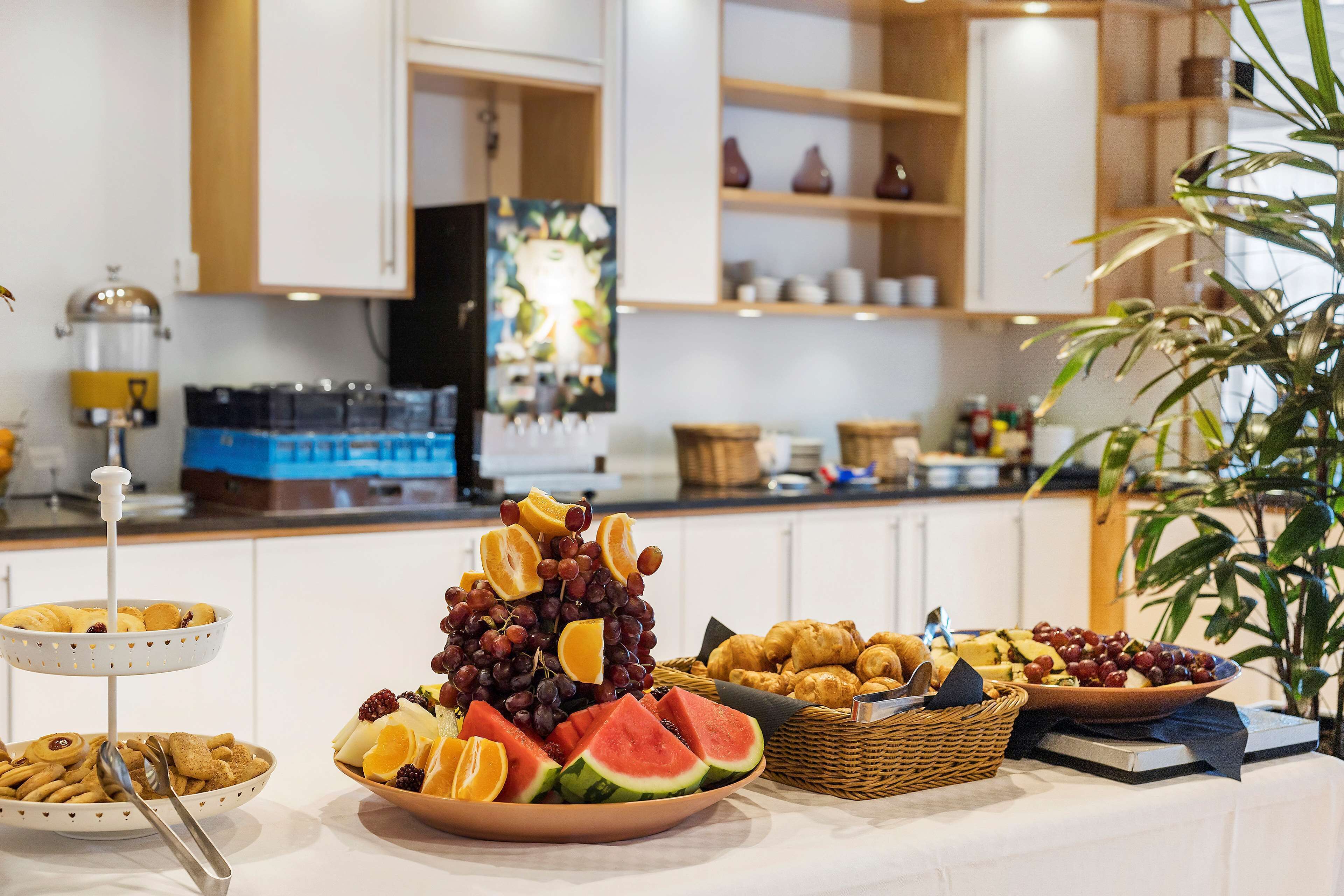 A buffet table with various fruits, pastries, and a coffee station.
