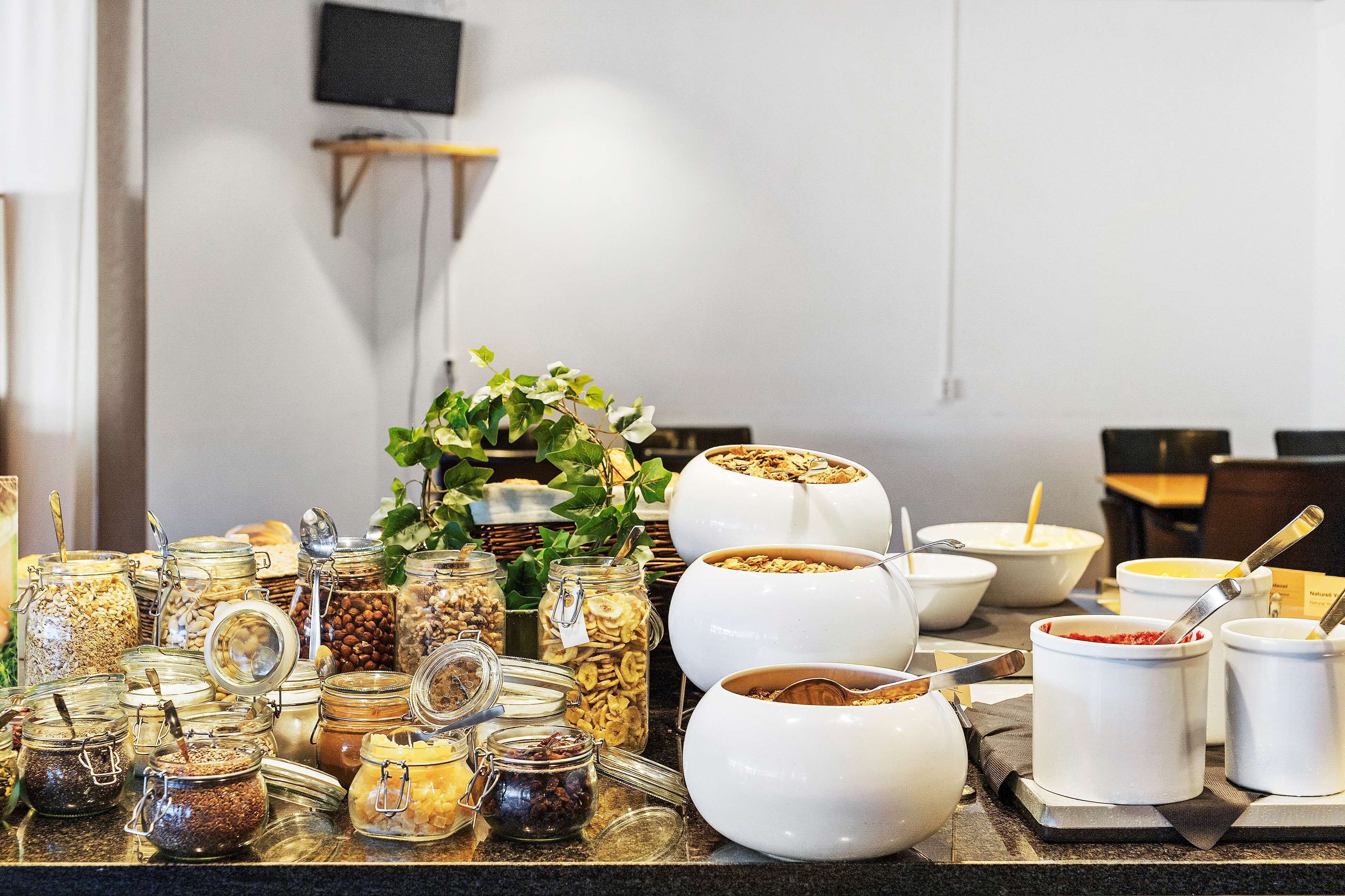 A buffet with various food items in jars and bowls, a potted plant, and a television in the background.