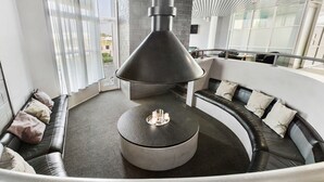 A modern lounge area with a round seating arrangement, a central fire feature, and large windows providing natural light. - Best Western Eurostop Orebro (Örebro)