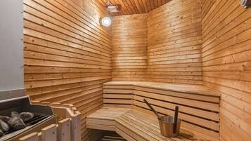 Sauna, jossa on puiset lauteet ja metallinen ämpäri.