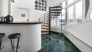 A modern kitchen with a curved bar area, a staircase, and a view of the outdoors. - Best Western Eurostop Orebro (Örebro)