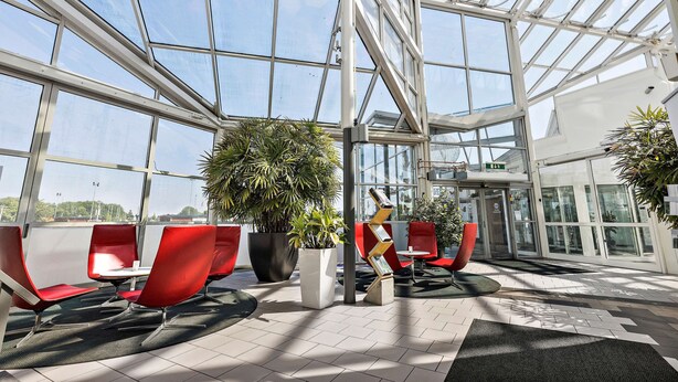 A spacious indoor area with a glass ceiling, red chairs, and potted plants. - Best Western Eurostop Orebro (Örebro)