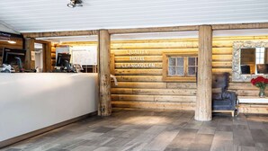 A reception area with a wooden log wall, a reception desk, and a seating area with a chair and a table. - Quality Hotel Leangkollen (Asker)