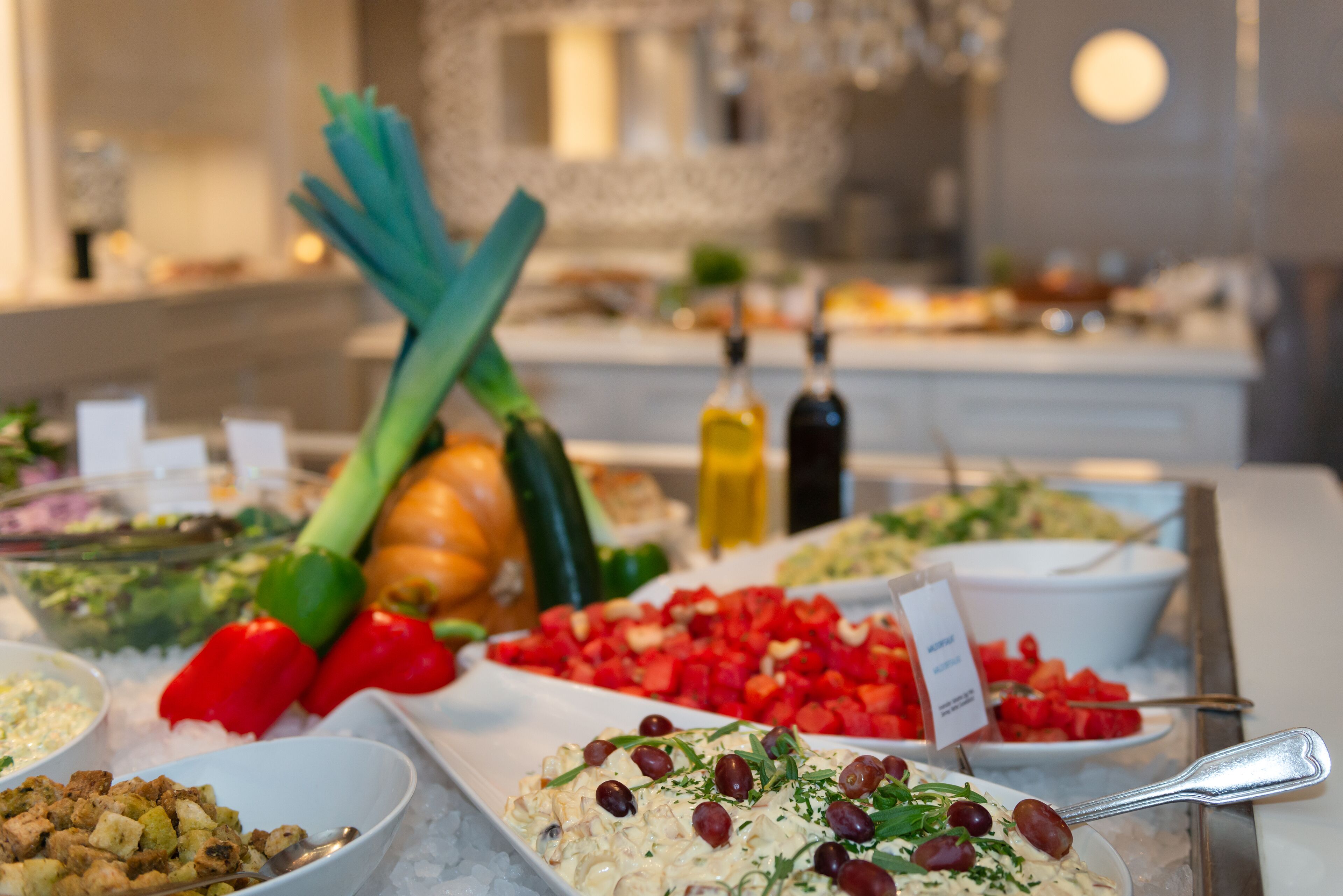 A buffet with various dishes including salads, fruits, and vegetables.
