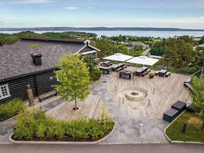 A wooden deck with outdoor seating, a fire pit, and a view of a lake. - Quality Hotel Leangkollen (Asker)