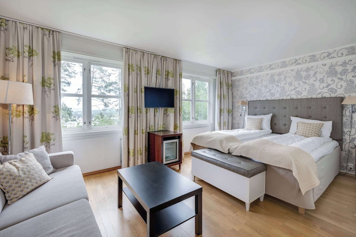 A hotel room with a bed, a sofa, a TV, and a small table.