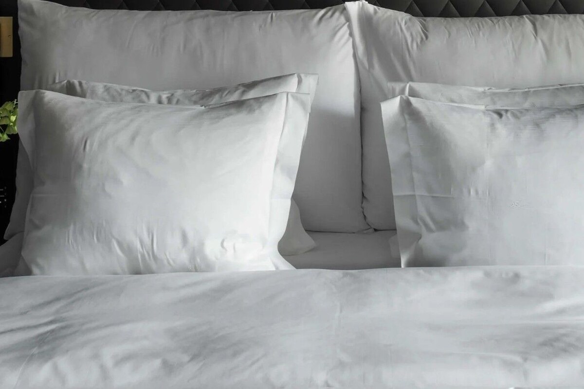 A bed with white bedding and pillows.