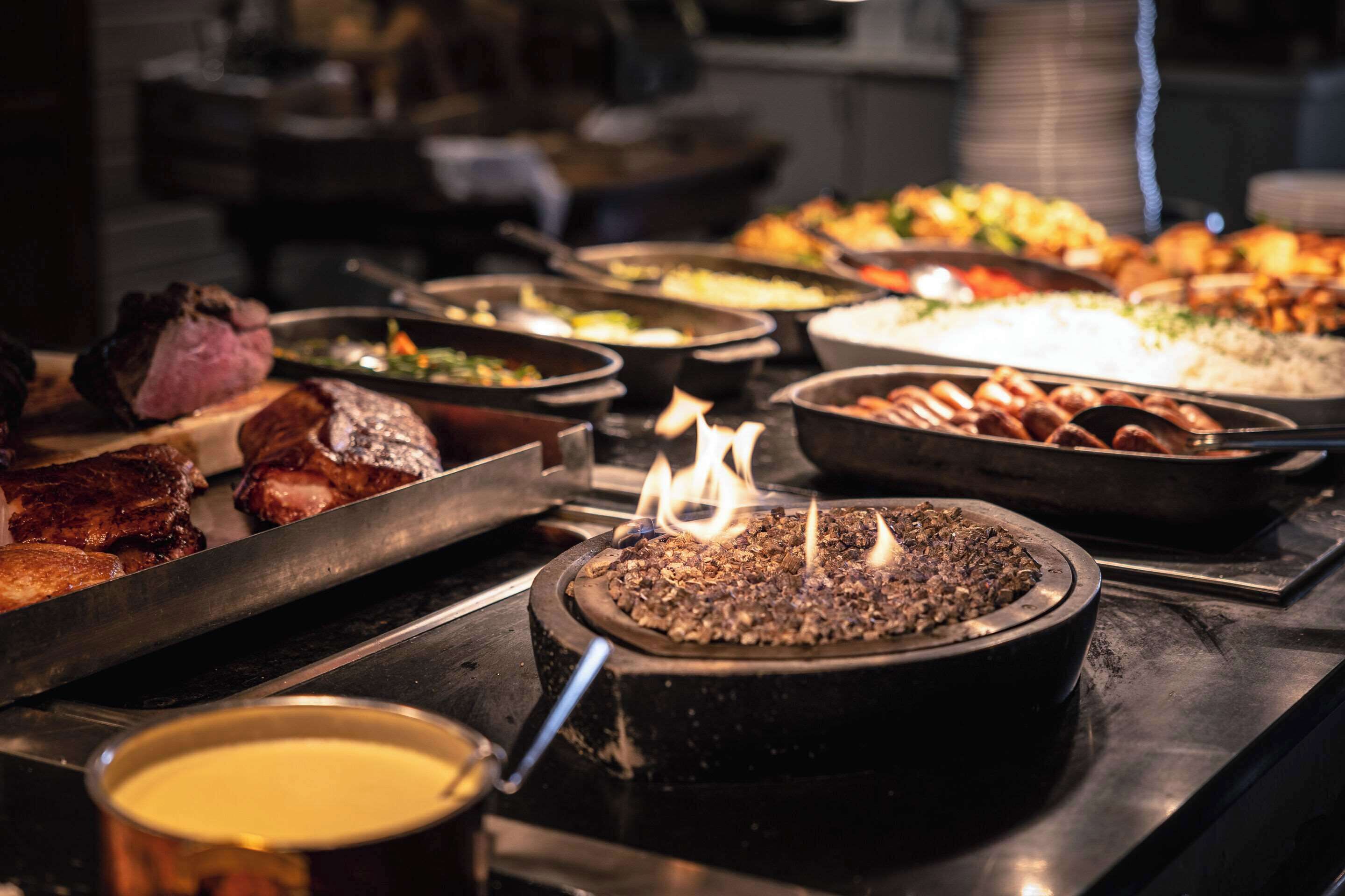 A buffet with various food items including meats, vegetables, and rice.