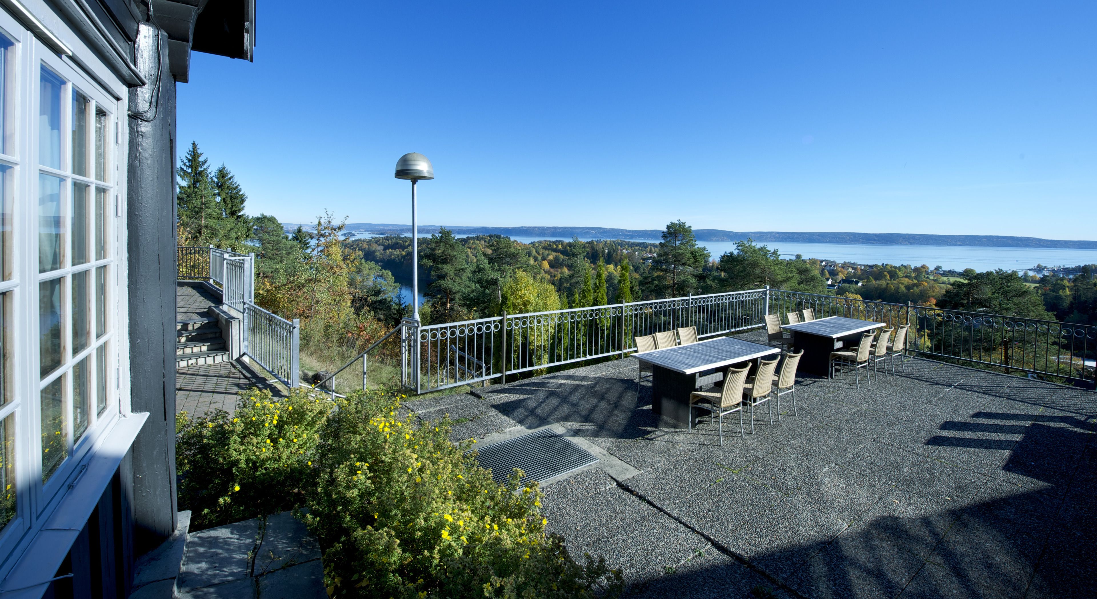 A rooftop terrace with outdoor seating and a view of a lake.