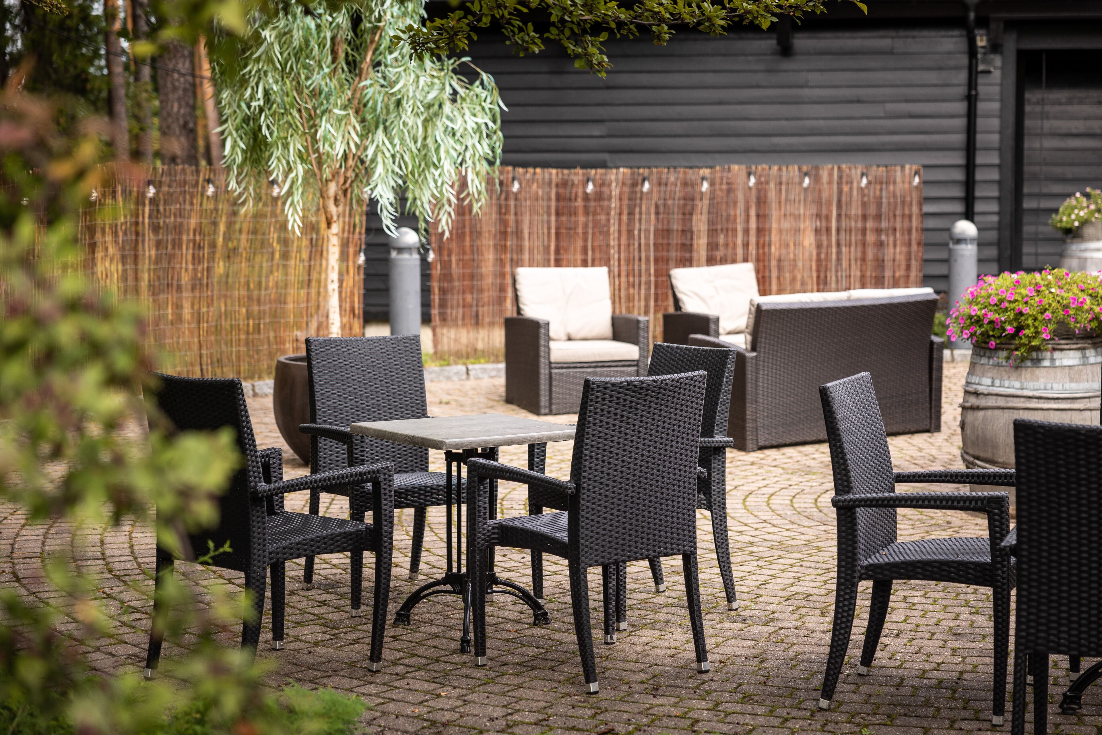 Un patio al aire libre con mobiliario de mimbre, una mesa y una planta colgante.