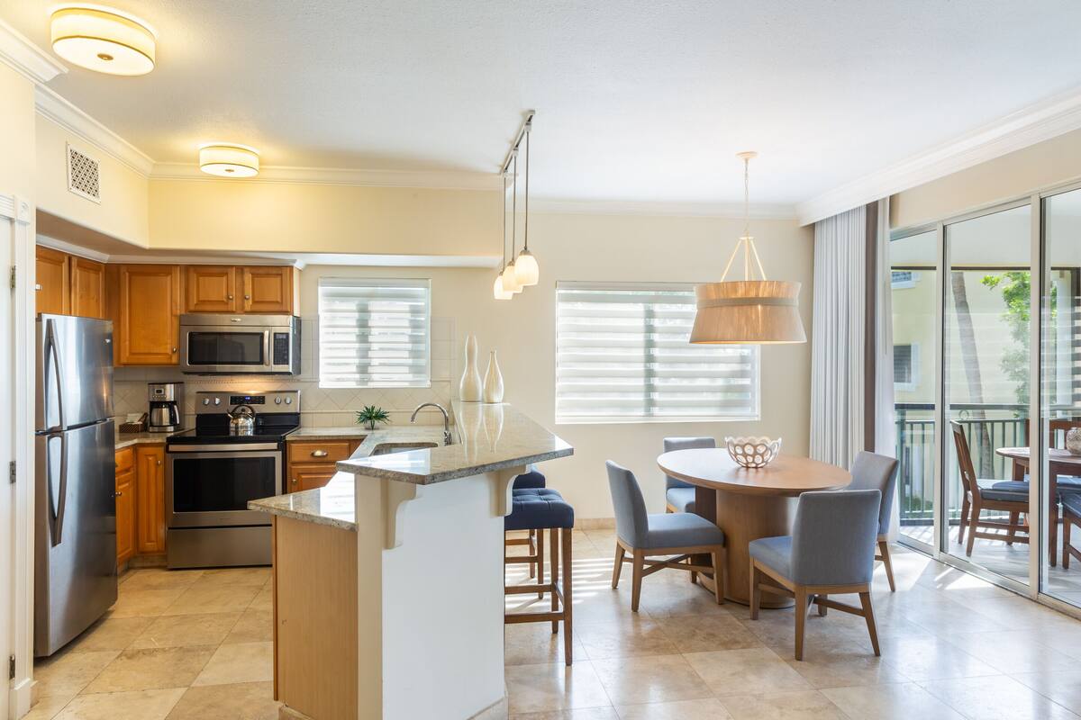 A modern kitchen with a central island, stainless steel appliances, and a dining area with a round table and chairs.