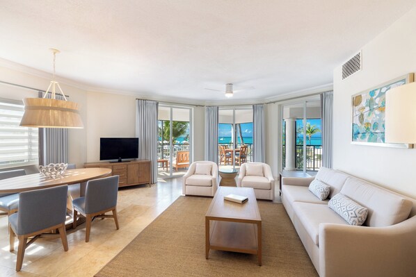 A modern living room with a flat-screen TV, a dining area with a table and chairs, and a sofa. - The Sands at Grace Bay (Providenciales)
