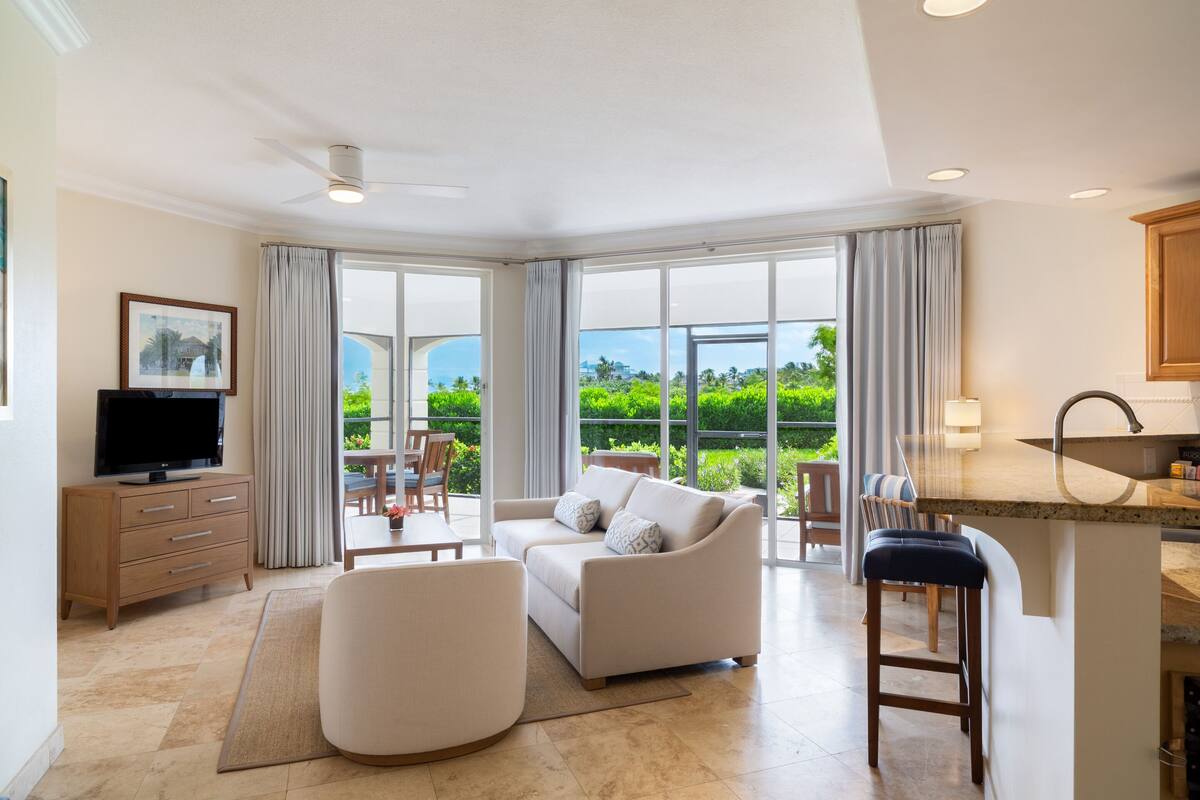 A modern living room with a sofa, a TV, and a dining area with a table and chairs.