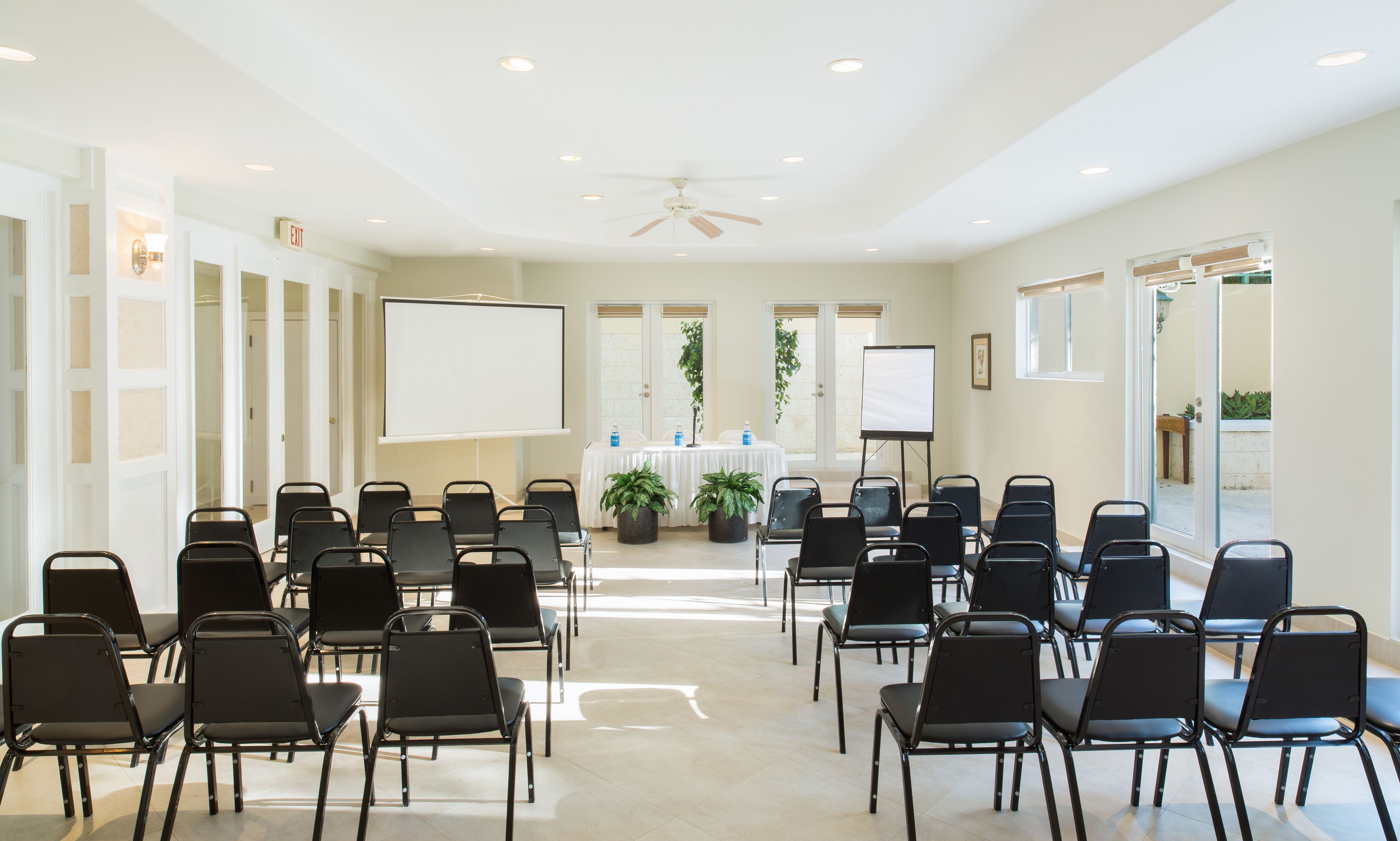 Une salle de conférence avec des rangées de chaises, un tableau blanc et un écran de projection.