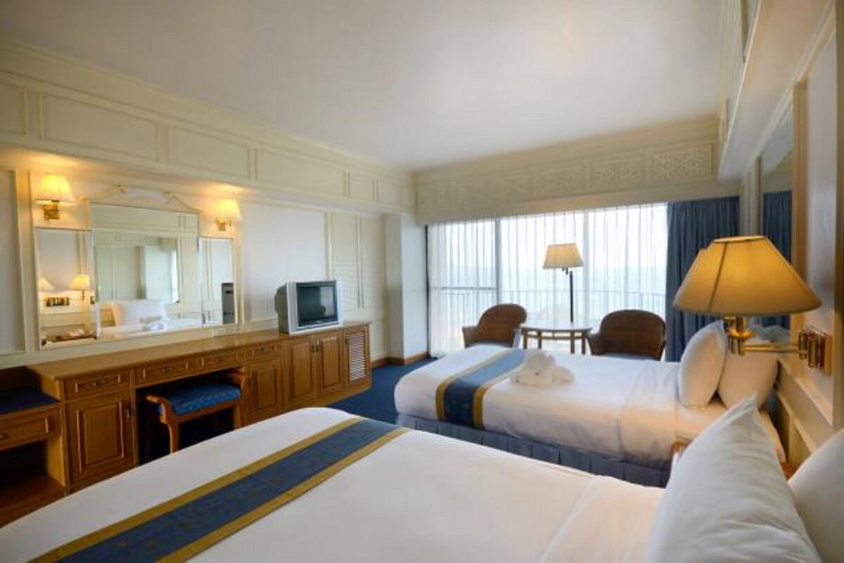 Une chambre d’hôtel avec deux lits, un bureau, une télévision et une fenêtre avec des rideaux.