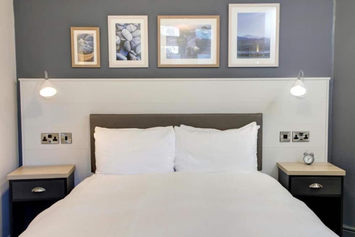 Escritorio, cortinas blackout y tabla de planchar con plancha