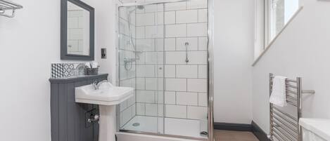 A modern bathroom with a glass-enclosed shower, a pedestal sink, and a toilet.
