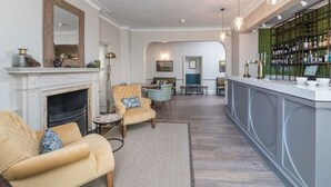Un salón amplio con chimenea, asientos cómodos y una zona de bar con estanterías.