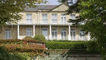 A multi-story building with a balcony, surrounded by lush greenery and a well-maintained garden.
