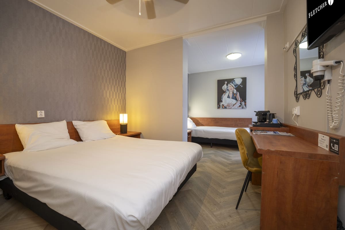 Une chambre d’hôtel avec un grand lit, un bureau avec un téléphone et une chaise.