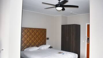 A bedroom with a bed, a ceiling fan, and a wardrobe.
