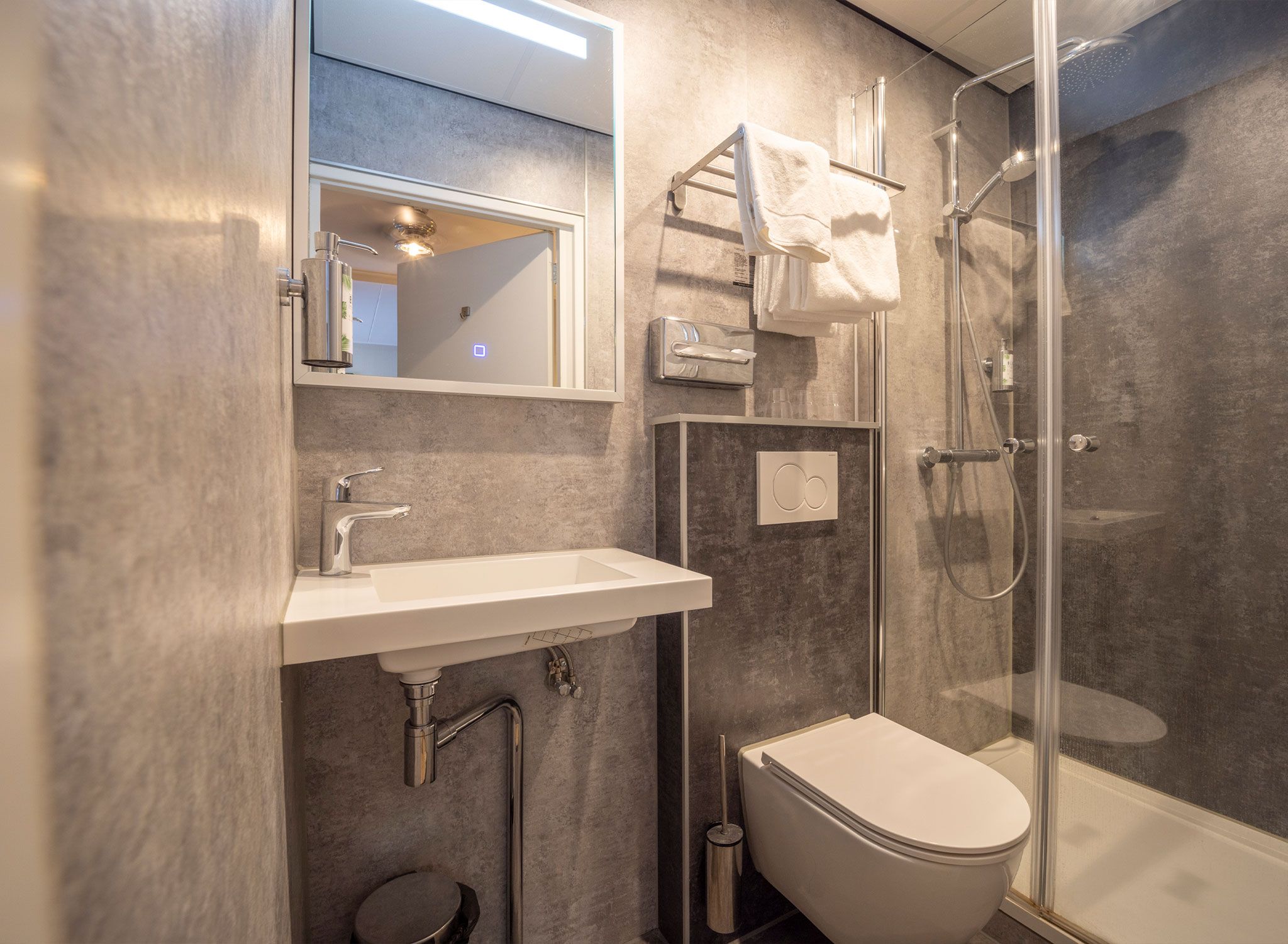 Une salle de bain moderne avec une douche à parois de verre, un lavabo blanc et des toilettes.
