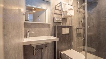 Une salle de bain moderne avec une douche à parois de verre, un lavabo blanc et des toilettes.