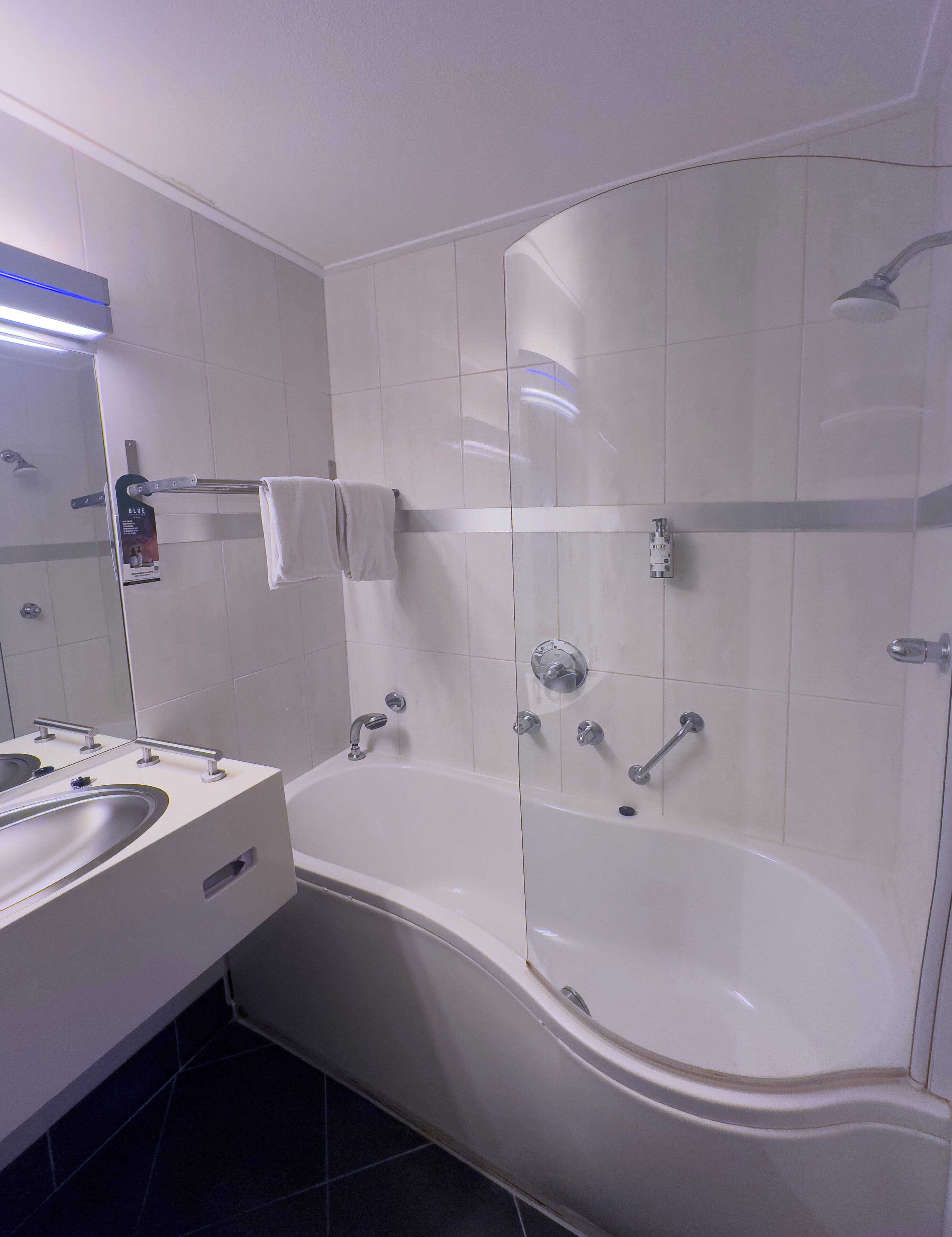 A modern bathroom with a large bathtub, a separate shower area, and a vanity with a mirror and sink.