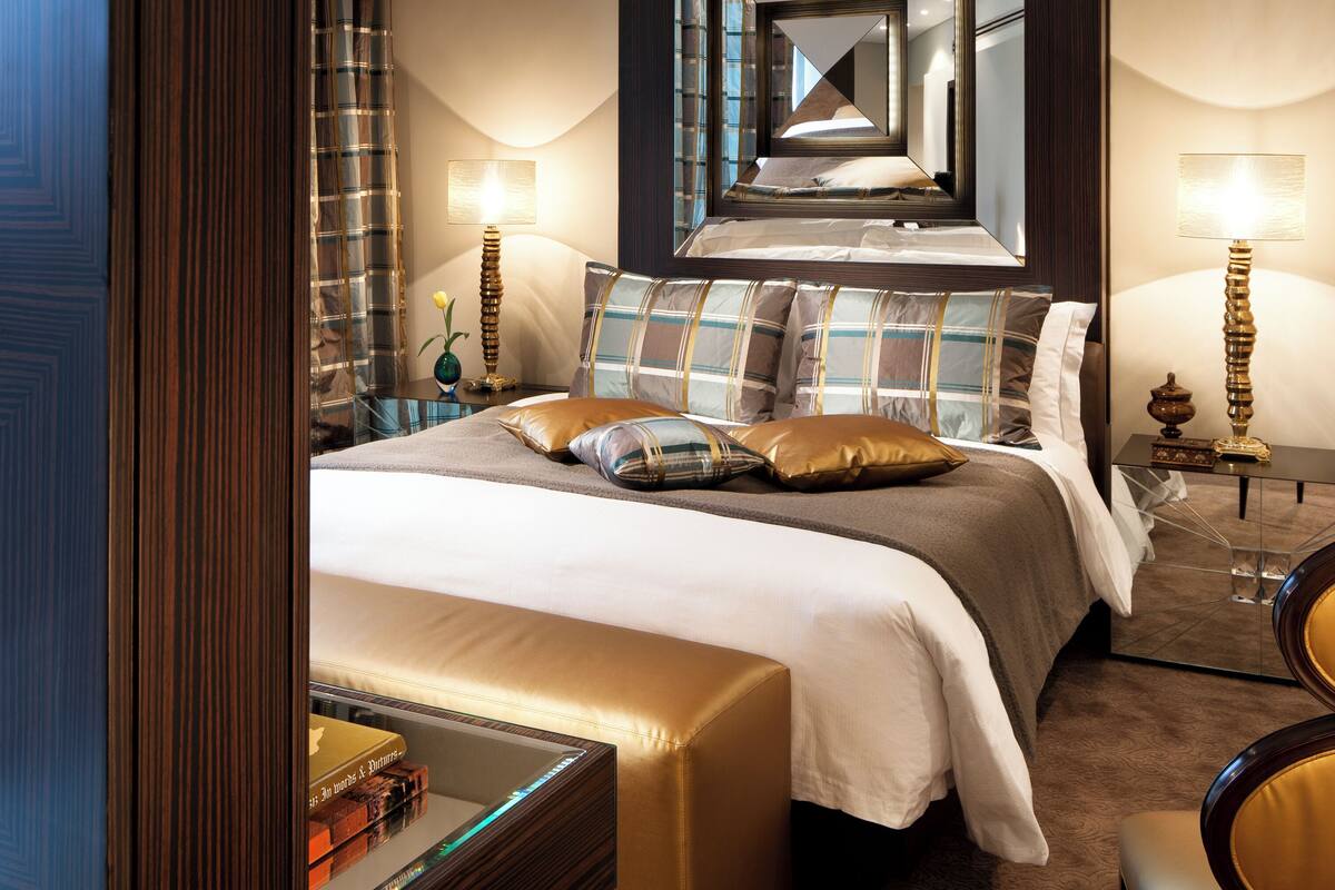 A modern hotel room with a large bed, a glass coffee table, and a seating area with a chair.