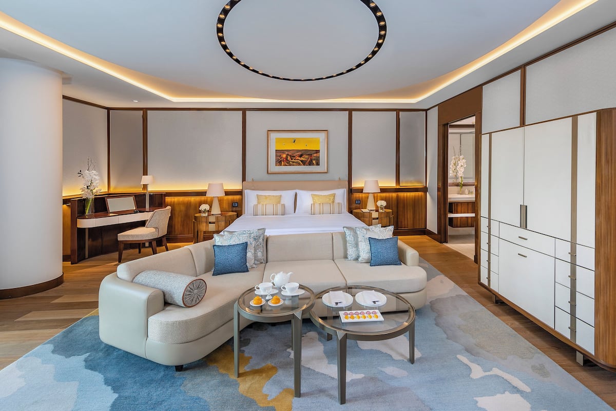 A modern hotel room with a bed, sofa, and a desk area.