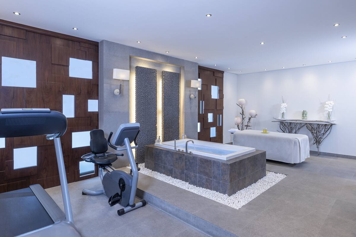 A modern bathroom with a bathtub, exercise equipment, and a vanity area.