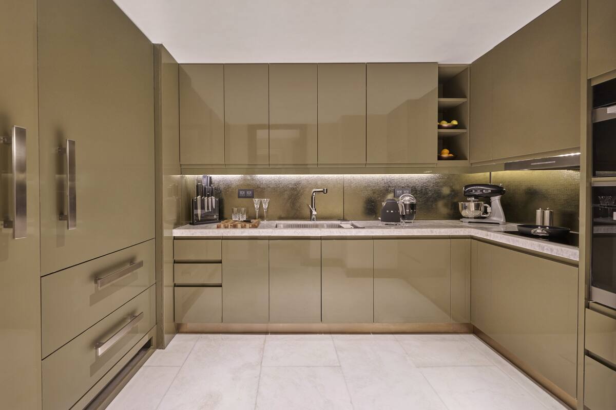 A modern kitchen with built-in appliances, a stainless steel sink, and a marble countertop.