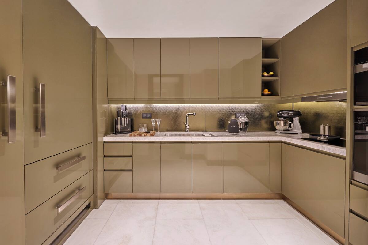 A modern kitchen with built-in appliances, a stainless steel sink, and a marble countertop.