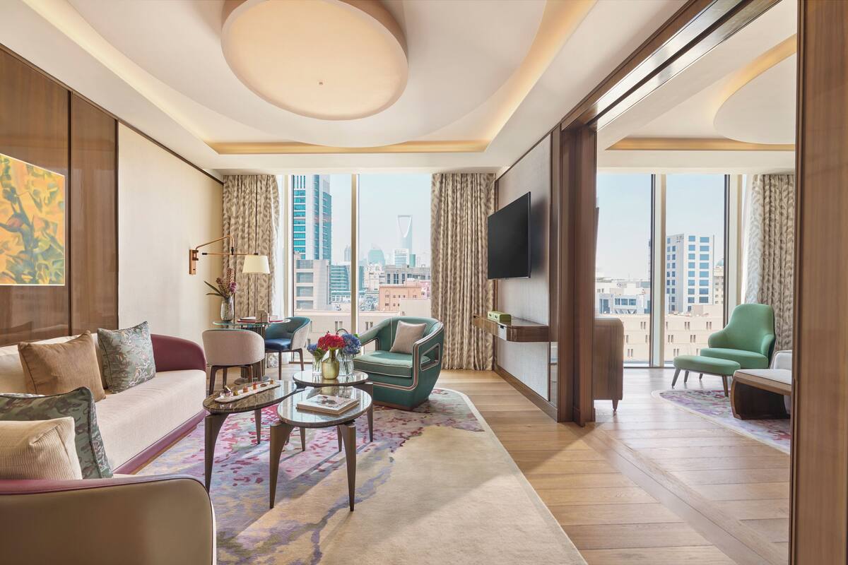 A modern living room with a city view, a flat-screen TV, and a variety of seating options.