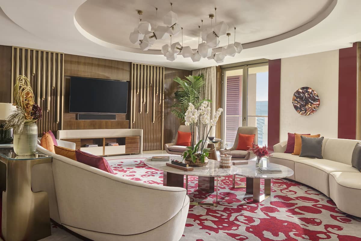A modern living room with a round coffee table, sofas, a TV, and a large window.