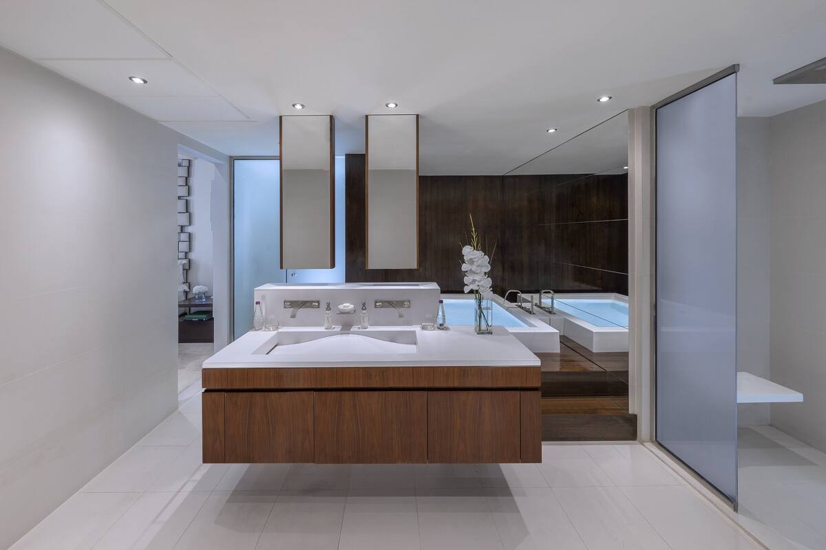 A modern bathroom with a wooden vanity, a large mirror, and a bathtub.