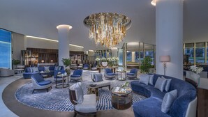 A spacious lobby with a large blue sofa, multiple armchairs, a coffee table, and a chandelier. - Mandarin Oriental Al Faisaliah, Riyadh (Riyadh)