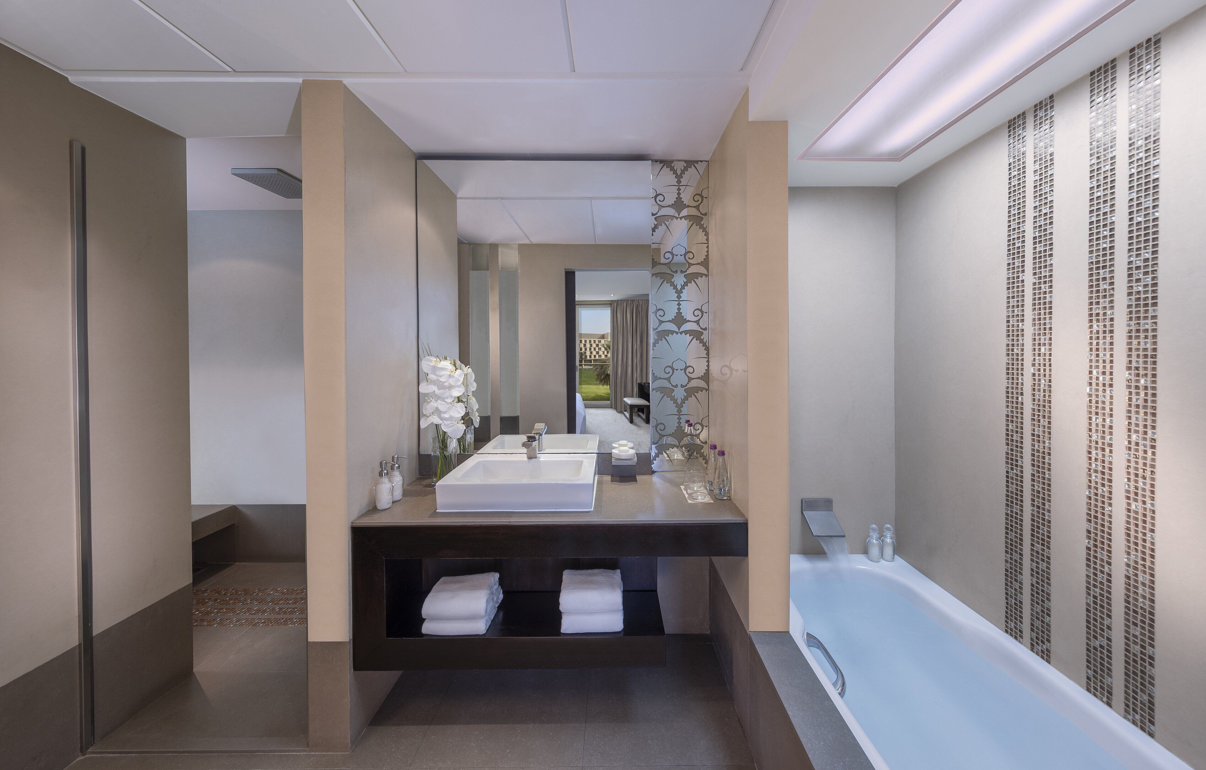 A modern bathroom with a large bathtub, two sinks, and a shower area.