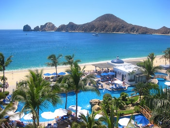 Relax by the oceanfront pool surrounded by palm trees and lounge chairs. at Pueblo Bonito Los Cabos Blanco - All Inclusive