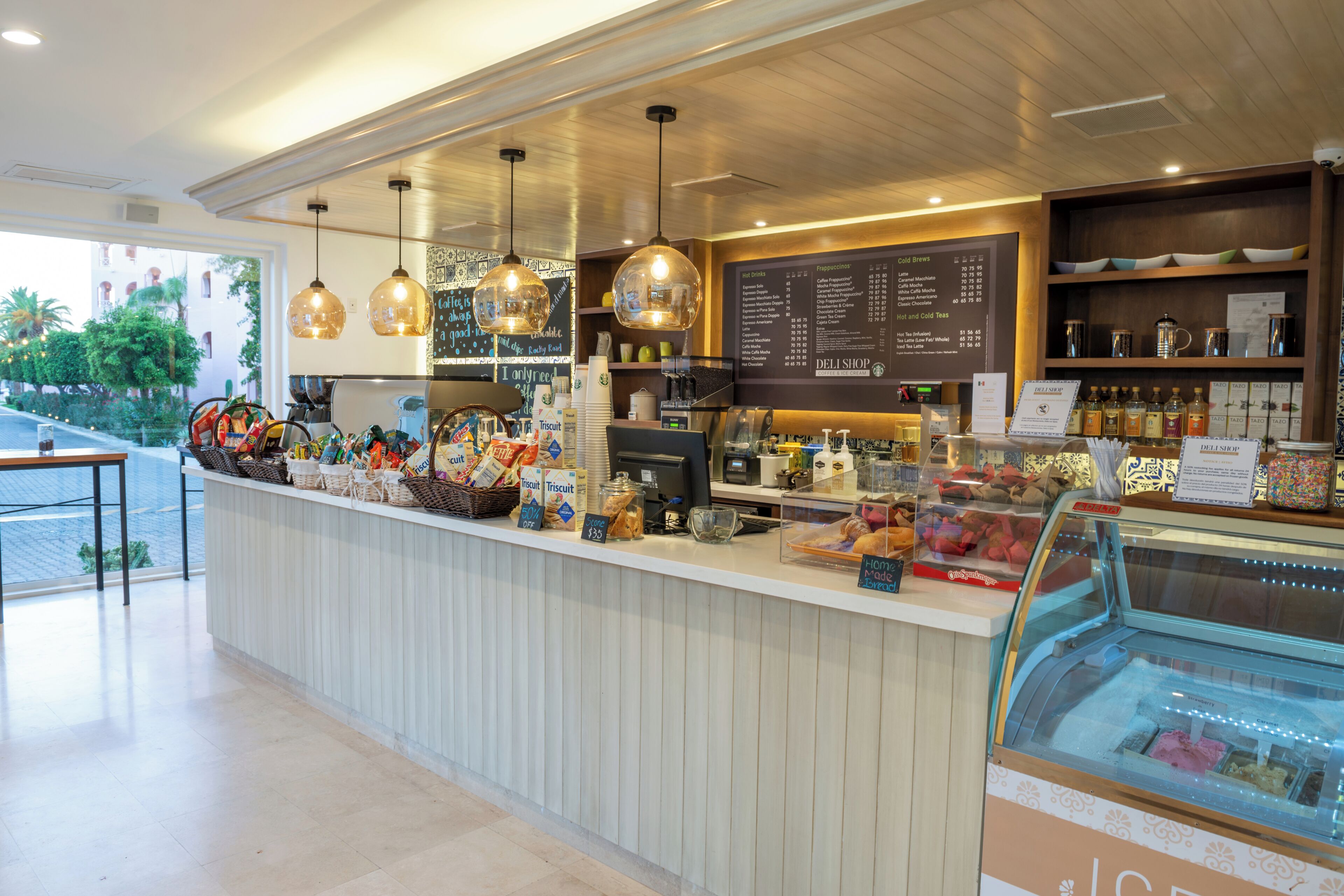 Une épicerie fine proposant une variété de produits alimentaires, un tableau affichant le menu et une vitrine remplie de desserts.